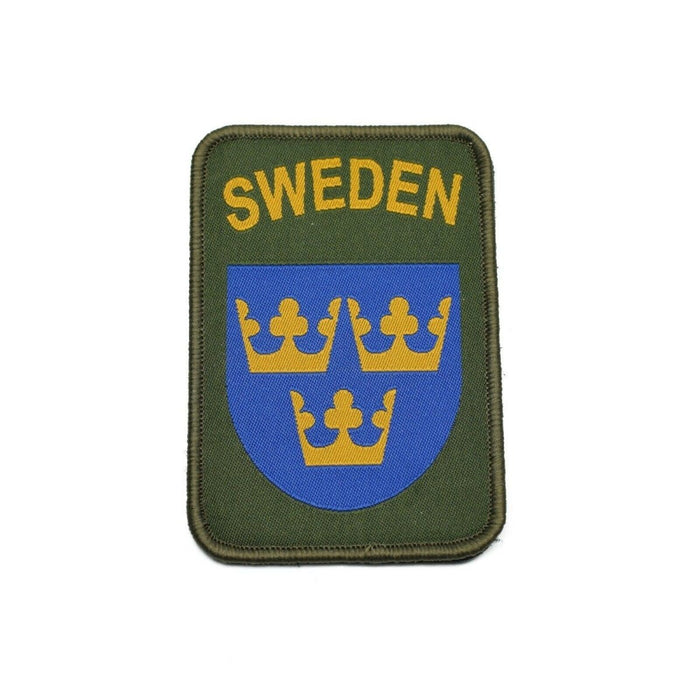 Écusson militaire suédois avec trois couronnes dorées sur bouclier bleu et fond vert olive avec texte SUÈDE.