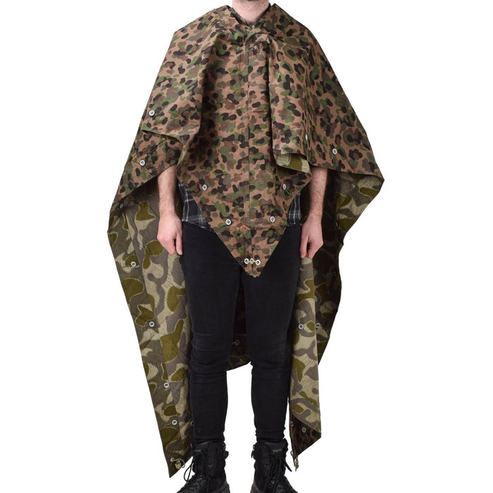 Personne portant une tente poncho camouflage vintage de l'armée autrichienne résistante à l'eau et à pois avec attaches de coin