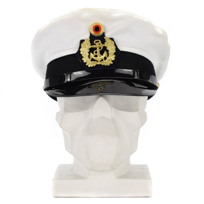Casquette d'officier de la marine allemande blanche avec insigne doré et visière noire posée sur une tête de mannequin blanche.