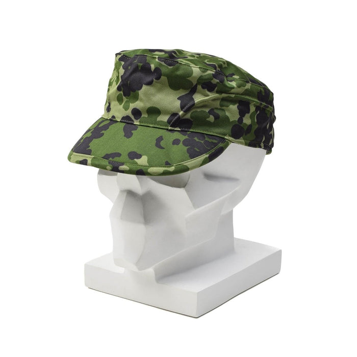 Casquette de campagne camouflage M84 de l'armée danoise originale avec oreillettes pliables présentée sur une tête de mannequin blanche.