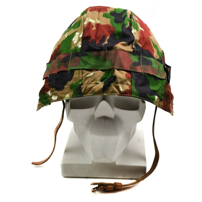 Originaler M71-Militärhelmüberzug der Schweizer Armee mit authentischer Alpenflage-Tarnung in Grün-, Braun- und Grautönen.